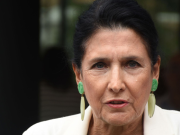 Президент, стоящий с зажженной спичкой в руках у сухого стога сена